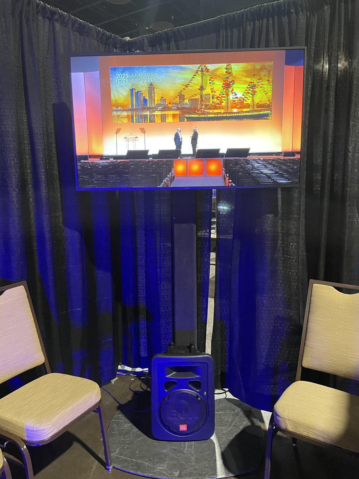 Teleprompter display showing a live stage view behind a black drape