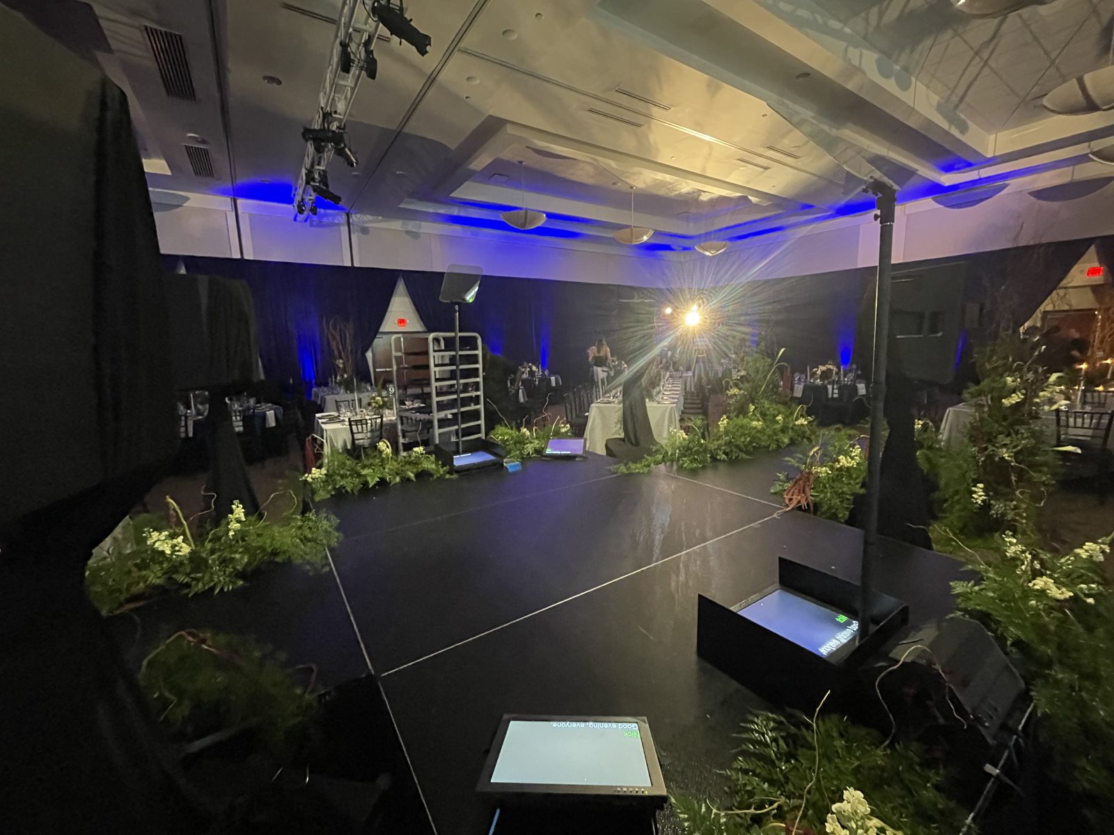 Ballroom stage with prompters and floral arrangements